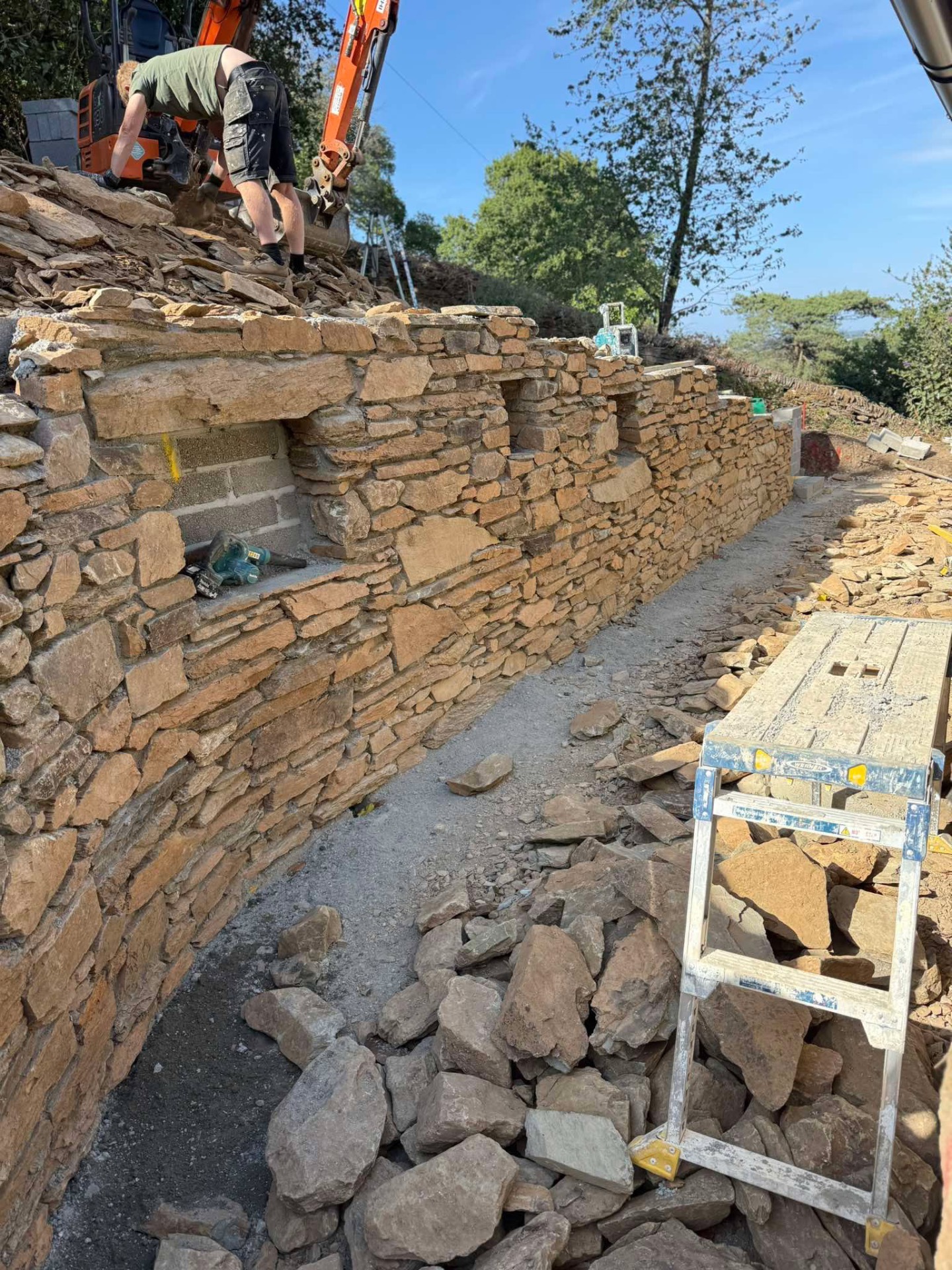 Traditional stone retaining wall being rebuilt with local stone